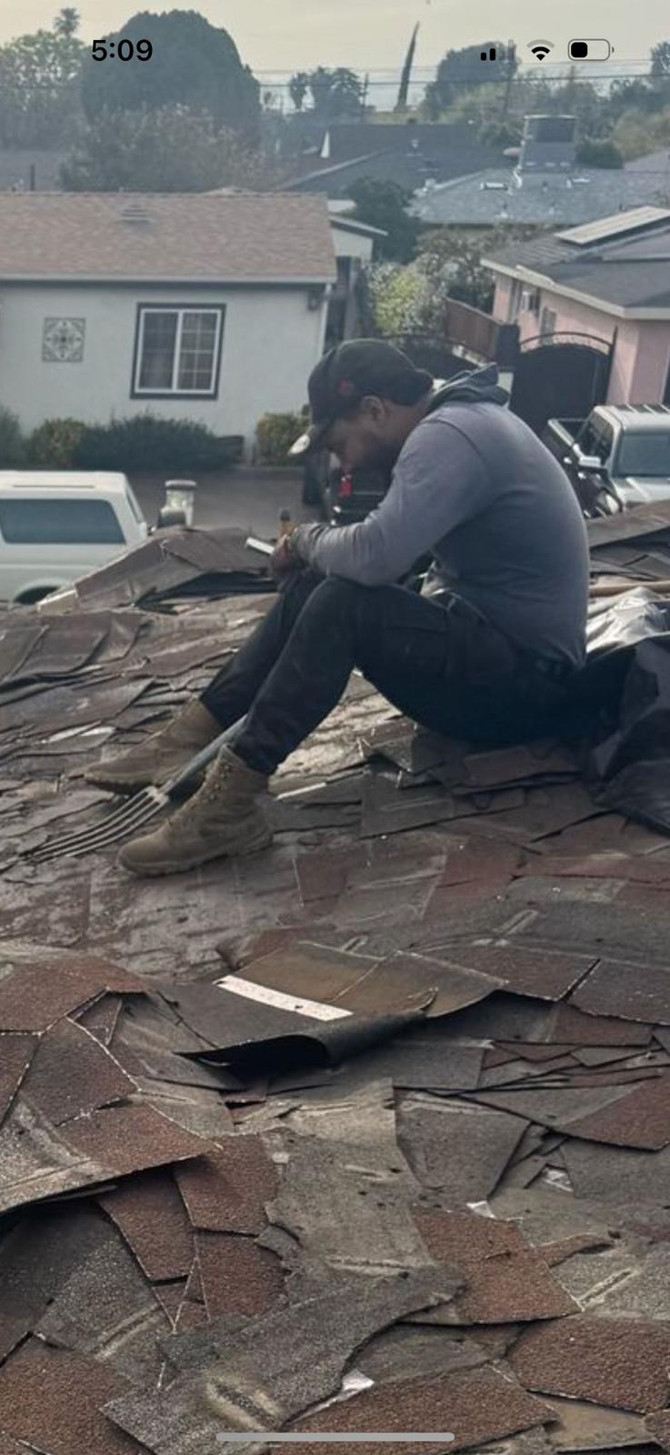 Roof replacement - worker tearing off old shingles